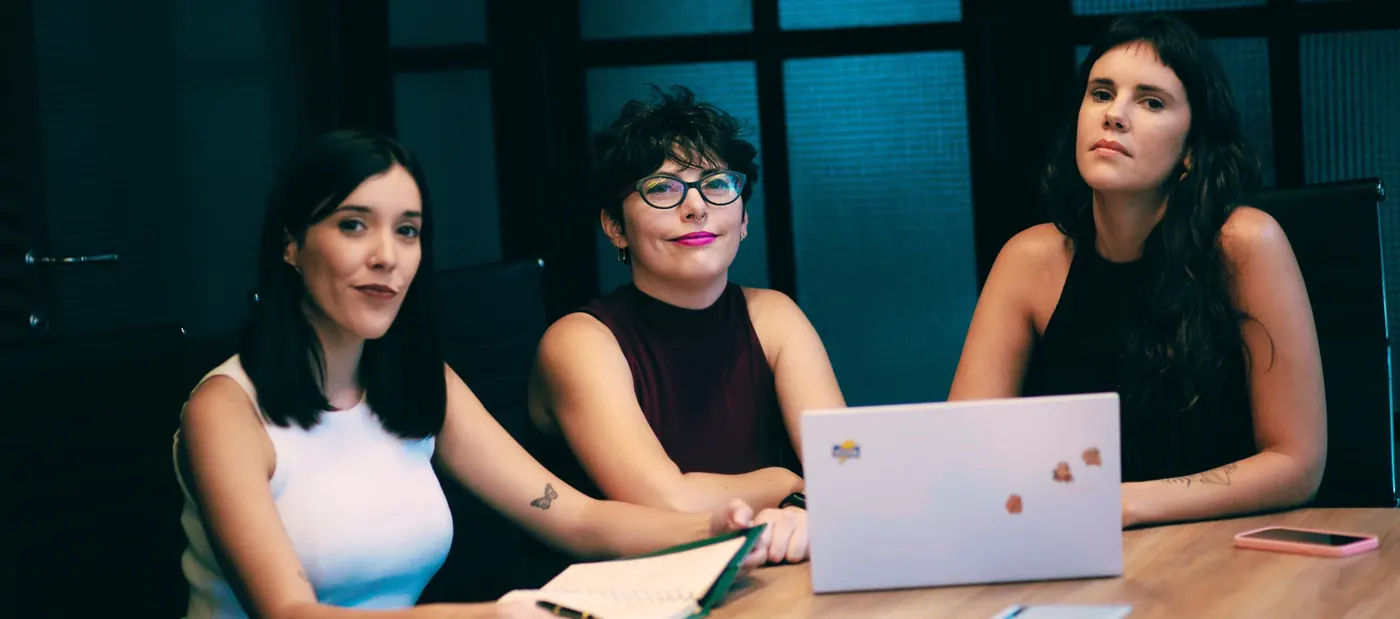 Micaela, Florencia y Daiana, las tres socias de Proyecto SHE, mirando a cámara en la mesa de reuniones
