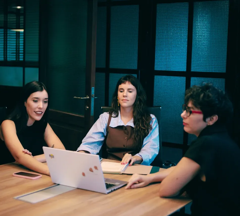 Reunión del equipo de SHE alrededor de una mesa con una notebook